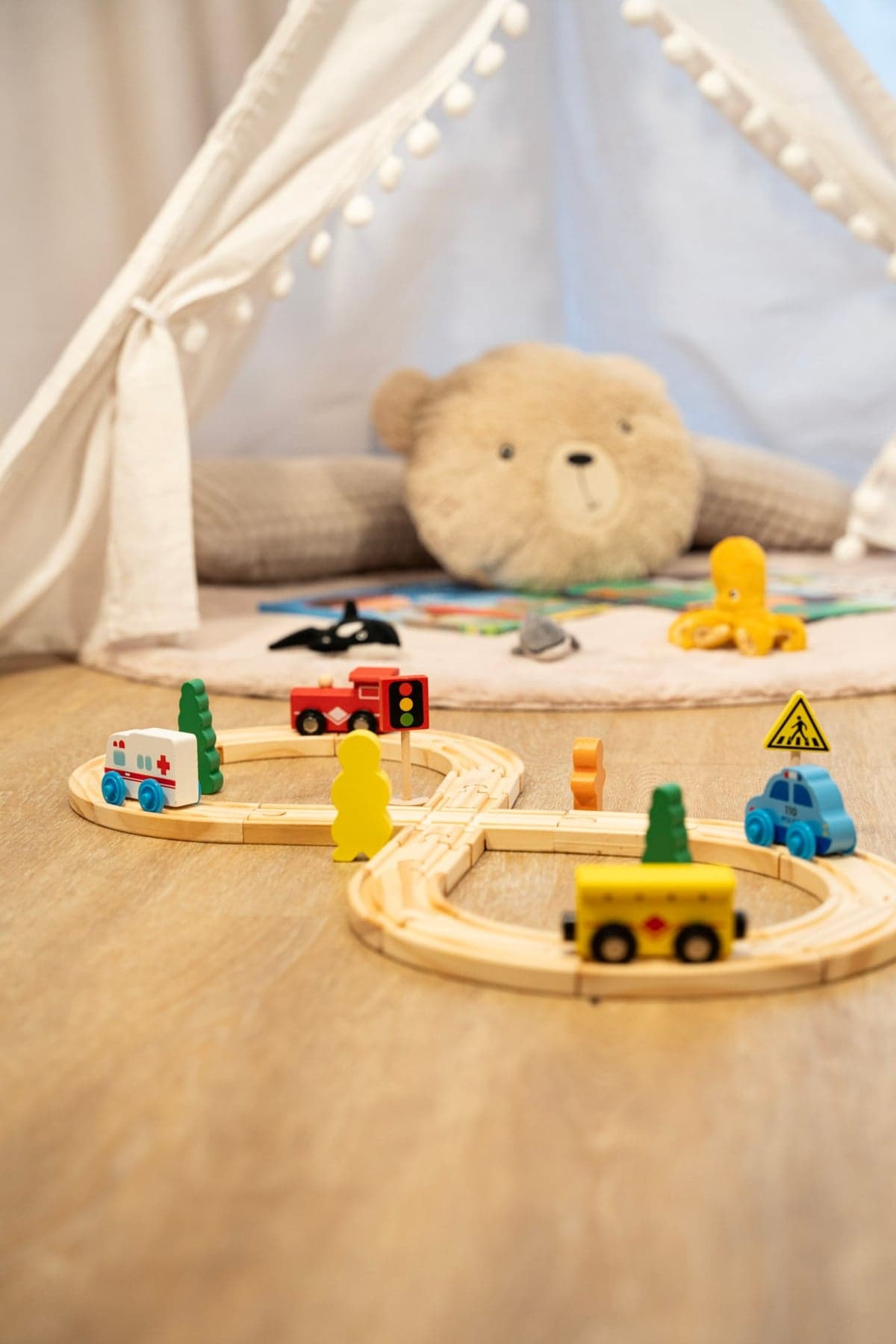 Holzeisenbahn mit Spielzeugautos vor einem Tipi-Zelt mit Teddybär
